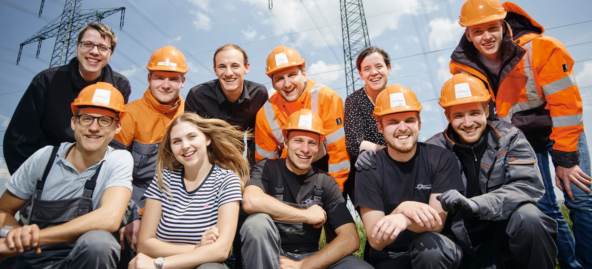 50Hertz-Team vor einem Umspannwerk, teils mit Schutzhelmen und Arbeitskleidung